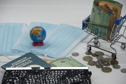 Quarantine in Kazakhstan. Tenge money with medical face masks, a globe, a card and a passport are on the table. The closure of borders and travel in Kazakhstan.