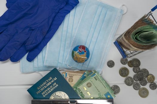 Quarantine in Kazakhstan. Tenge money with medical face masks, a globe, a card and a passport are on the table. The closure of borders and travel in Kazakhstan.