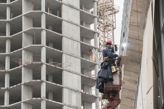 Moscow,Russia 10.07.2020:A construction worker who works as a welder, builds or repairs the facade of a building or structure.Construction and repair work on the street outside.A welder welds a metal