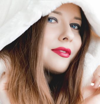 Young woman in fluffy fur coat with hood wrap, warm winter clothing for fashion and Christmas holidays design