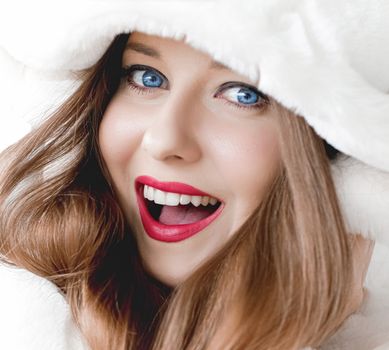 Young woman in fluffy fur coat with hood wrap, warm winter clothing for fashion and Christmas holidays design