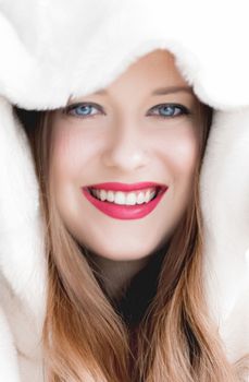 Young woman in fluffy fur coat with hood wrap, warm winter clothing for fashion and Christmas holidays design