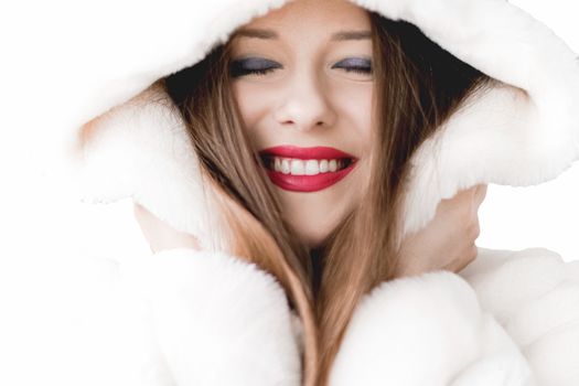 Young woman in fluffy fur coat with hood wrap, warm winter clothing for fashion and Christmas holidays design