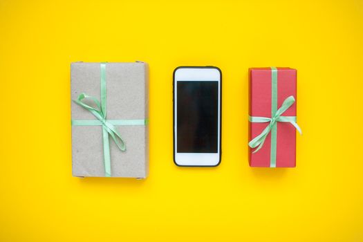 Online shopping. Phone and wrapped boxes with gifts on yellow background