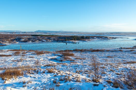 River on the plain in Iceland. The banks are covered with snow. Winter landscape, open spaces