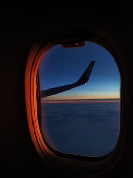 View from the airplane window flying over the sea at sunset.