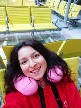 A cheerful girl takes a selfie in the airport departure hall before the flight.