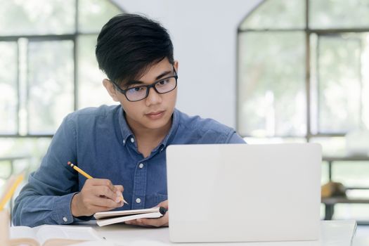 Young collage student using computer and mobile device studying online. Education and online learning.