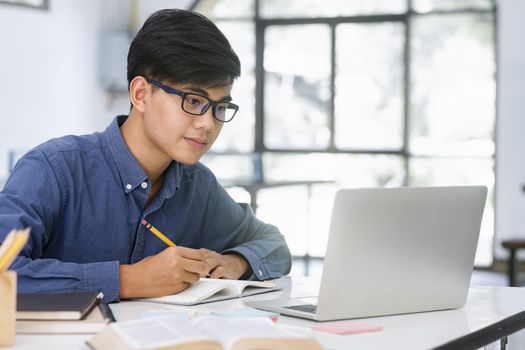 Young collage student using computer and mobile device studying online. Education and online learning.