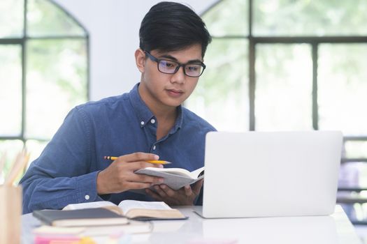 Young collage student using computer and mobile device studying online. Education and online learning.