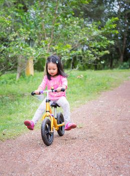 Little girl learns to riding balance bike on slope in the park