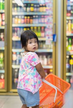little girl hold the basket and walking in minimart to shopping