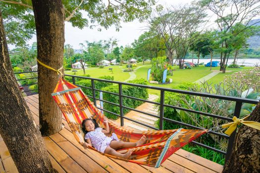 little asian girl in dress lying on cradle with nature park background