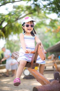 Asian little girl having fun on seesaw at playground