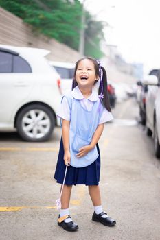 Portrait of happy little girl in Thai school uniform standing in the car park, ready back to school