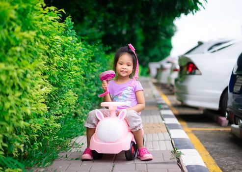Asian little girl enjoys playing car on footpath