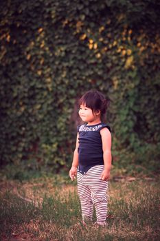 Full length of beautiful little girl in dress standing and posing over green background