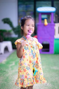 Portrait of little asian girl holding and eating donuts outdoor