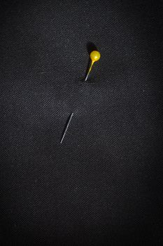 Pin with yellow head in black fabric