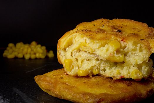 Broken corn pancakes close up on black background