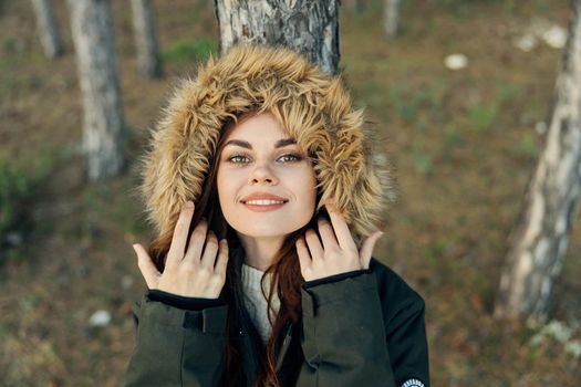 A woman with a hood on her head in nature is leaning against a tree in the forest. High quality photo