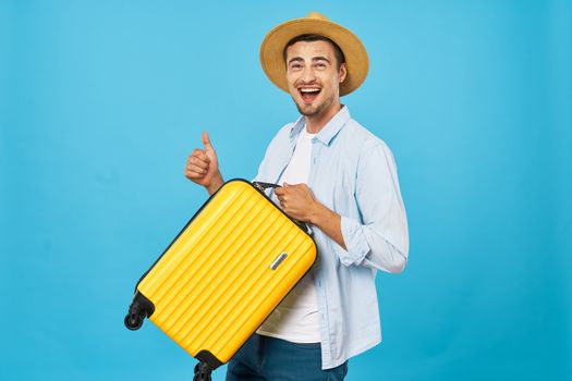 Happy traveler with a suitcase shows the thumb