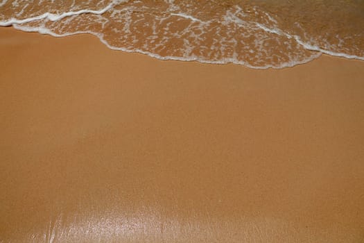 Look from the top corner Bubble waves hit the beach on the wet sand.