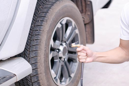 Close up man hand holding mechanic inflating tire and checking air pressure with gauge pressure in service station