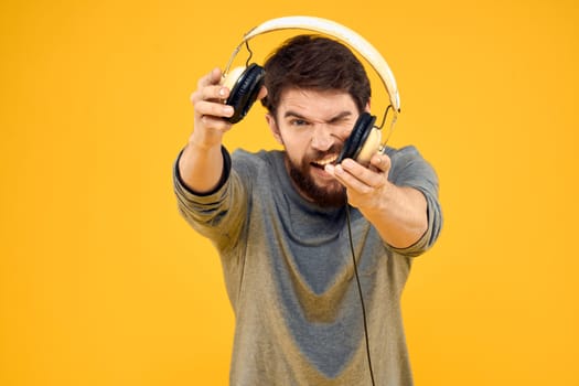 Man in headphones listens to music technology lifestyle fun people yellow background. High quality photo