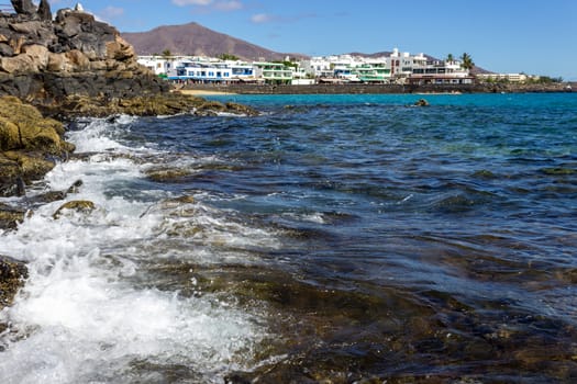 Lava rocks on the coastline of Playa Blanca at Canary island Lanzarote, Spain. The sky is blue.