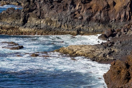 Rocky coastline Los Hervideros in the south west of canary island Lanzarote, Spain with rough sea, lava caves and multi colored volcanic rocks