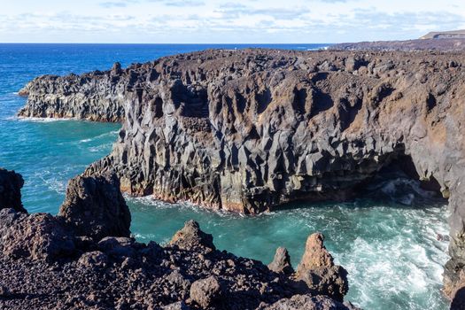 Rocky coastline Los Hervideros in the south west of canary island Lanzarote, Spain with rough sea, lava caves and multi colored volcanic rocks