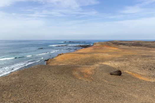 Scenic view at the coastline in the natural park of Jandia (Parque Natural De Jandina) on canary island Fuerteventura, Spain with gravel, lava rocks and rough sea with waves