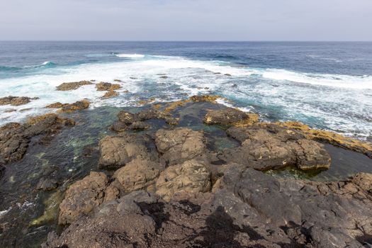 Panoramic view at the coastline in the natural park of Jandia (Parque Natural De Jandina) on canary island Fuerteventura, Spain with gravel, lava rocks and rough sea 