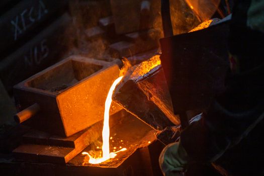 Close-up view of industrial chill casting with selective focus. The process of for filling out mold with molten metal.