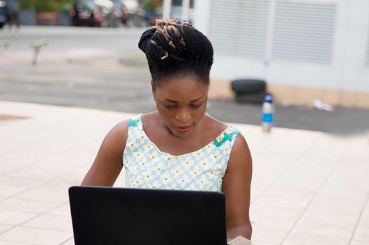 Young businesswoman sitting outside and working with her laptop...