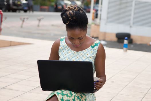 Young businesswoman sitting outside and working with her laptop...