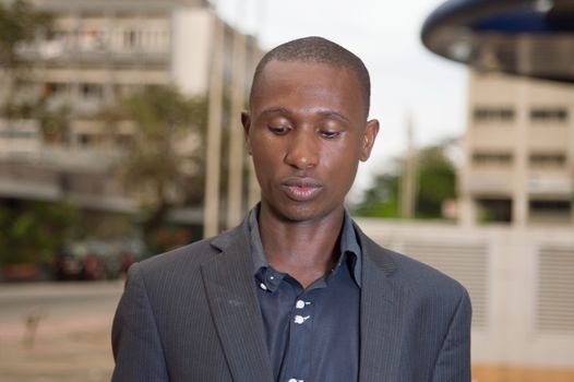 young businessman standing outside and looking at something down.