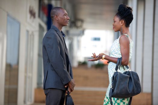 Businessman and businesswoman discussing work standing face to face and speaking with gestures.