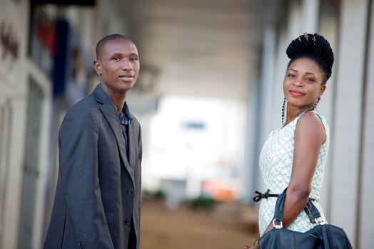 Businessman and businesswoman discussing work standing face to face watching the camera together