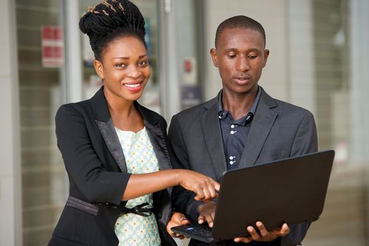 portrait of happy business people standing at office working on a laptop.