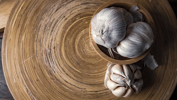 The garlic in wood bowl  on wood table for food content.