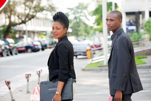 business partners walking together outside with a laptop in the young woman's hand.