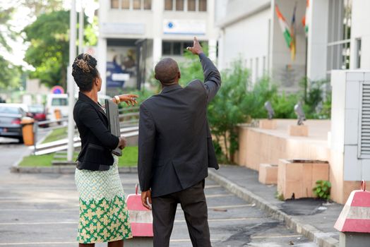 young businessman shows something to his colleague in front of a building.