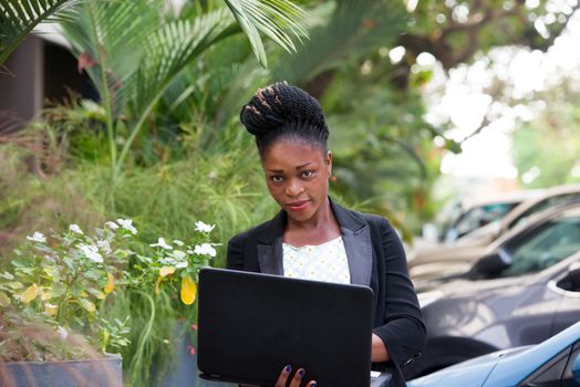 young happy businesswoman with a laptop standing outside.