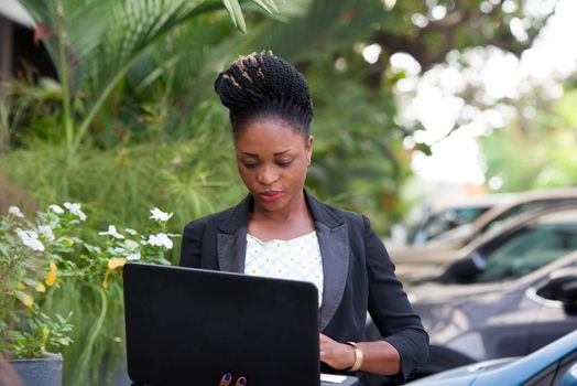young happy businesswoman with a laptop standing outside.