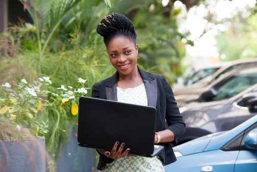 young happy businesswoman with a laptop standing outside.