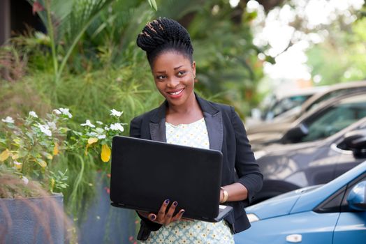 young happy businesswoman with a laptop standing outside.