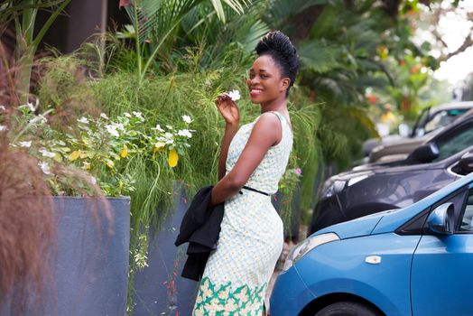 young happy businesswoman standing on the street and holding a white flower in the hand