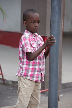 child, sad and lonely standing in the street against a metal